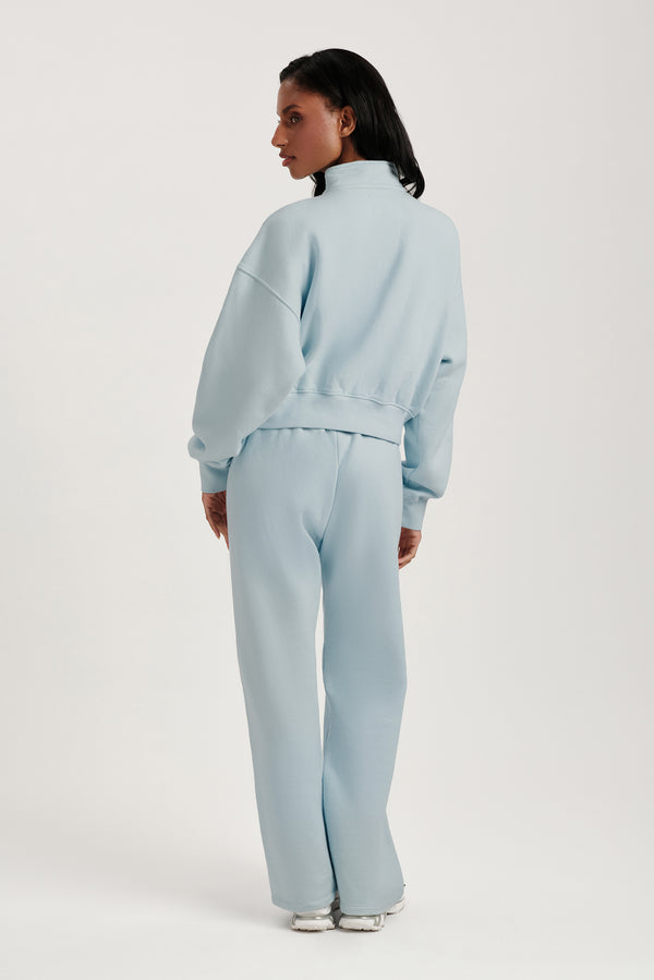 Person wearing a light blue tracksuit on a white background