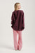 Person wearing a burgundy oversized sweatshirt and pink pants on a light gray background
