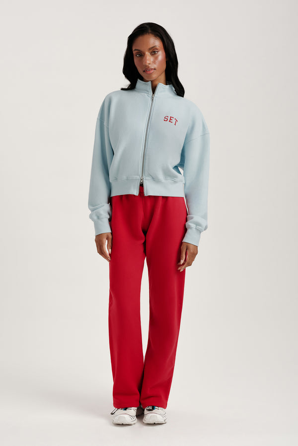 Person wearing a light blue tracksuit with 'SET' logo on a white background