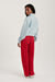 Person wearing a light blue sweatshirt and red pants on a white background