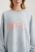 Person wearing a light blue sweatshirt with 'SET' in pink letters.
