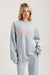 Woman wearing a light blue sweatshirt with 'SET' printed in pink on a plain background