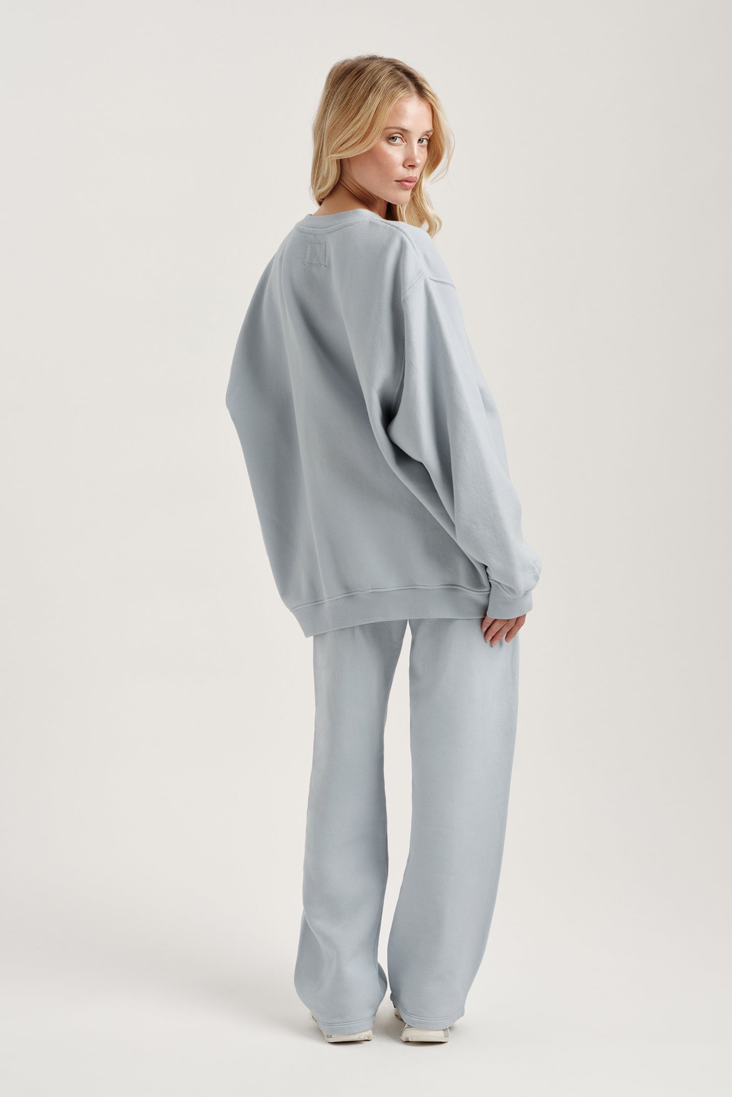 Woman wearing a light blue oversized sweater and pants on a white background