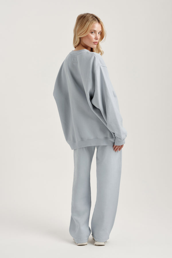 Woman wearing a light blue oversized sweater and pants on a white background