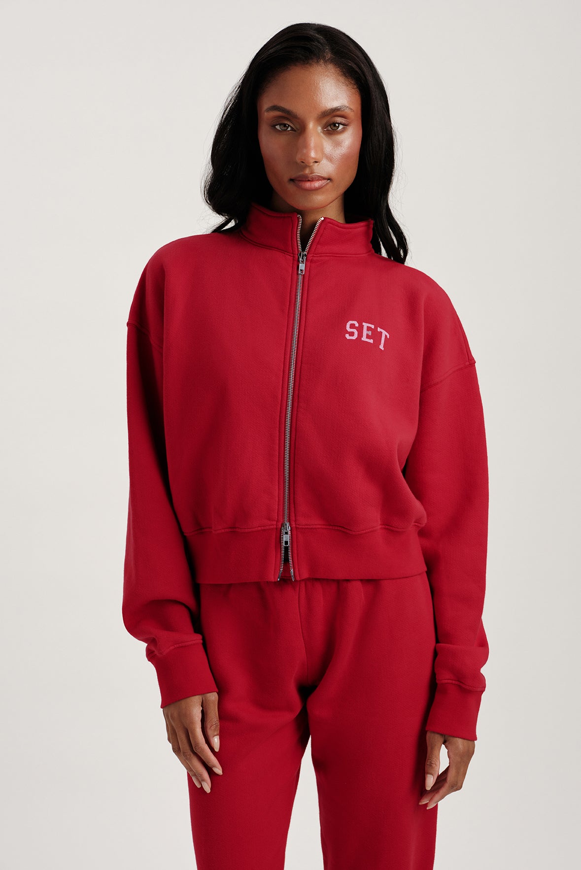 Person wearing a red tracksuit with 'SET' logo on a white background