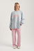 Woman wearing a light blue sweatshirt with 'SET' logo and pink pants on a white background
