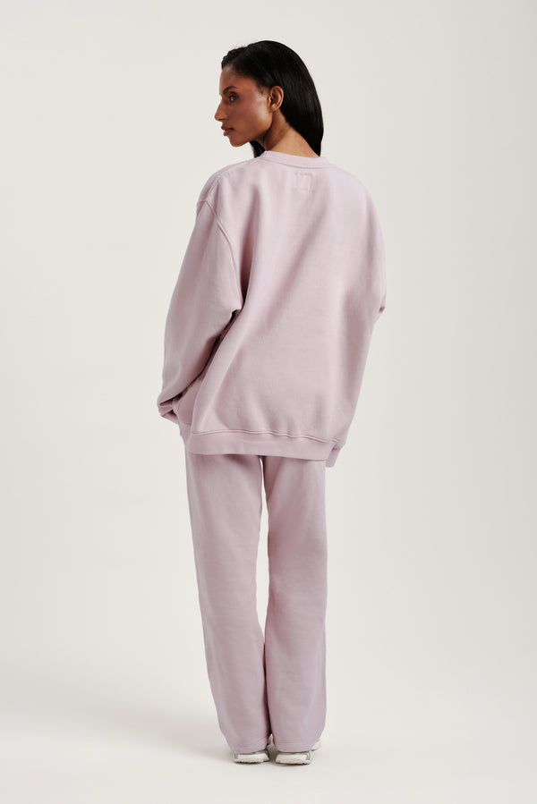 Person wearing a light pink sweatshirt and pants on a white background