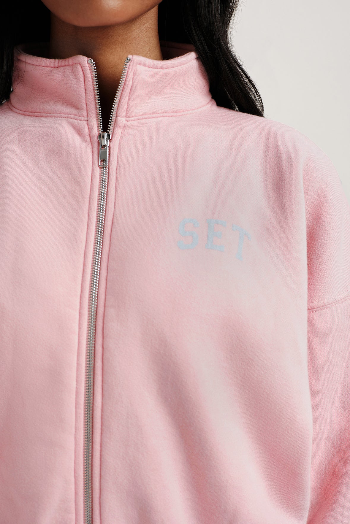 Close-up of a pink jacket with 'SET' branding on a neutral background