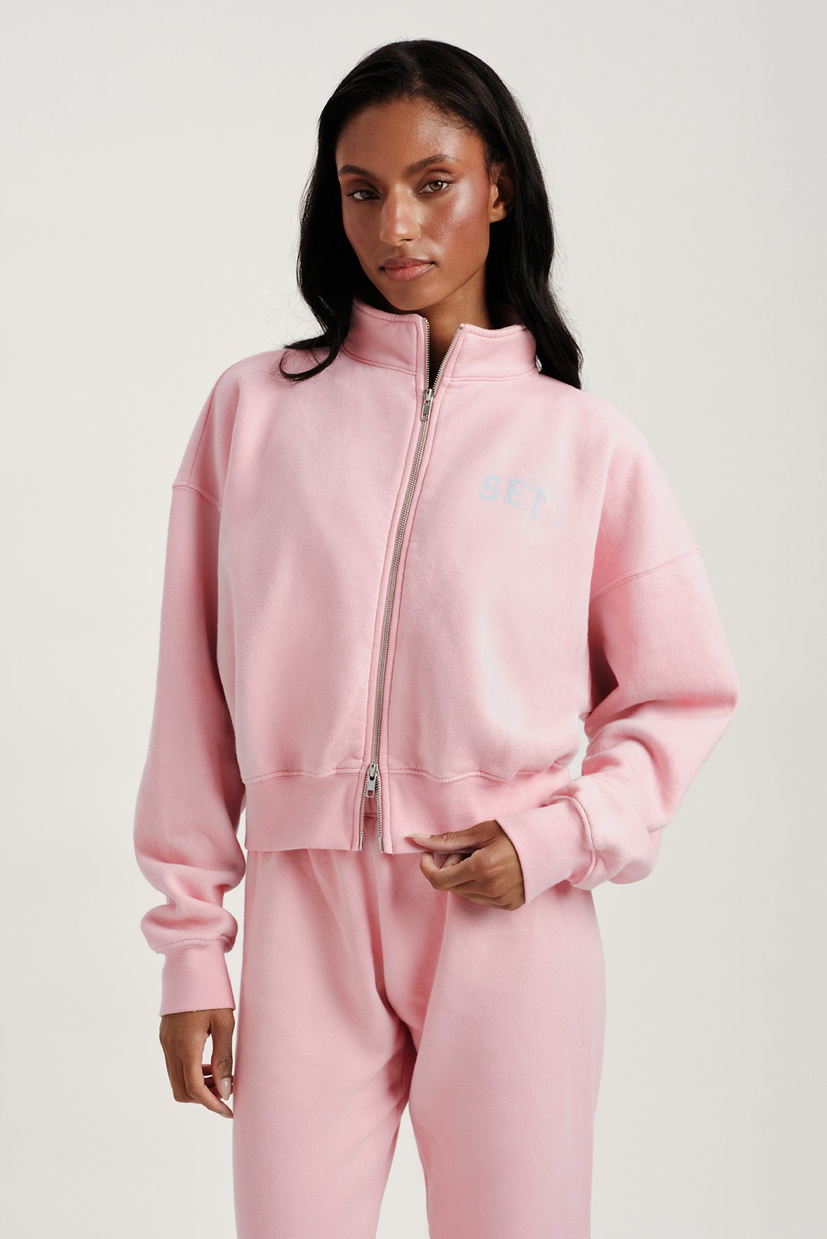 Woman wearing a pink tracksuit against a plain background