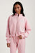 Woman wearing a pink tracksuit against a plain background