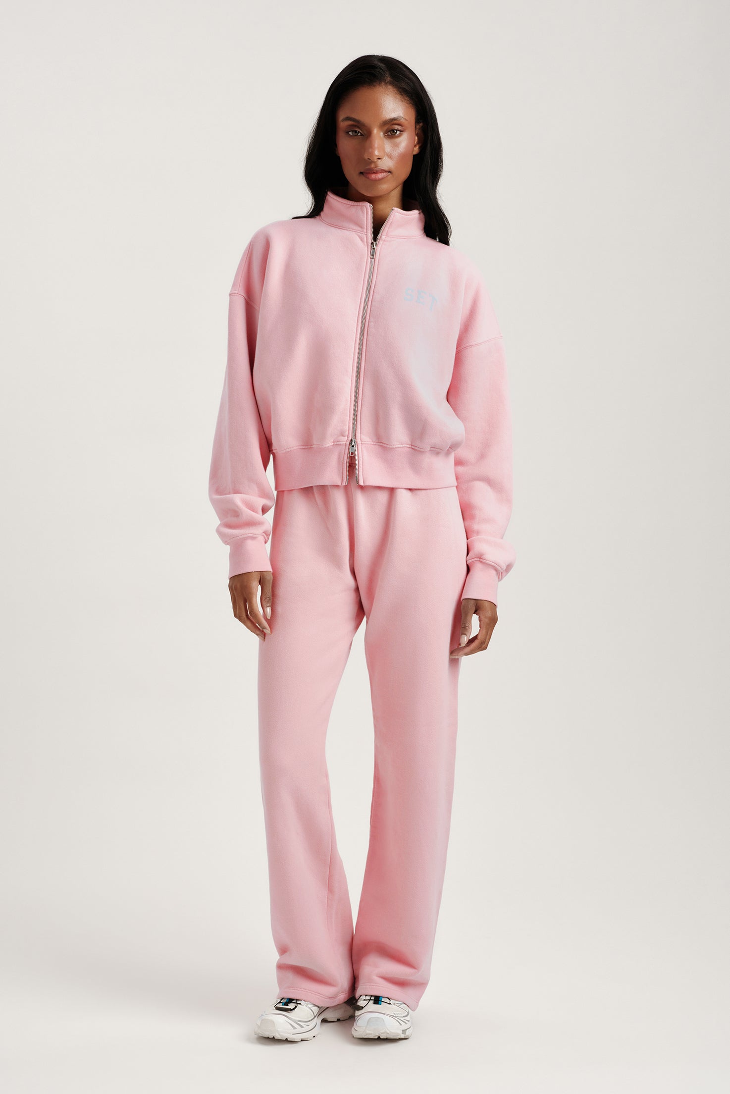 Person wearing a pink tracksuit on a white background