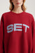 Red sweatshirt with 'SET' text worn by a person on a light background