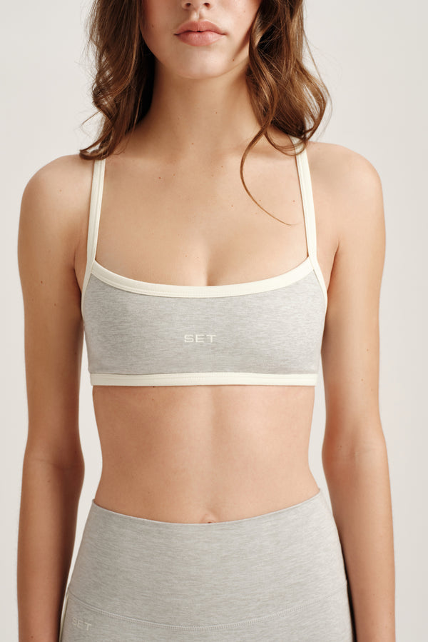 Woman wearing a gray sports bra and leggings with 'SET' branding on a white background