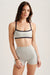 Woman wearing a gray sports bra and shorts set on a plain background <model-info>Bella wears a size XS and is 5’7, 23” waist, 32AB bust.</model-info>
