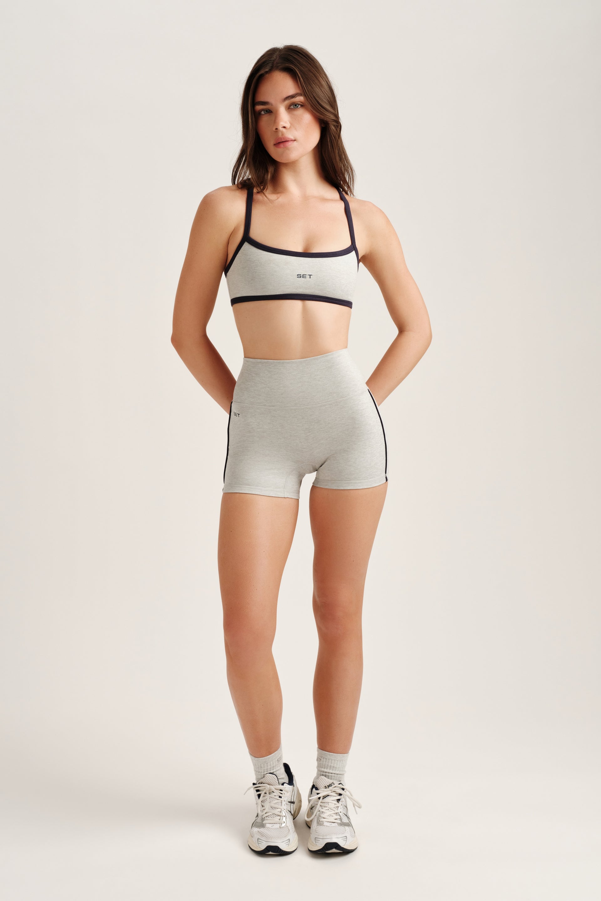 Woman wearing a sports bra and shorts on a plain background