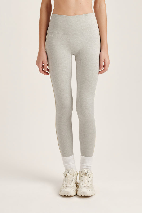 Person wearing light gray leggings and white sneakers on a plain background 