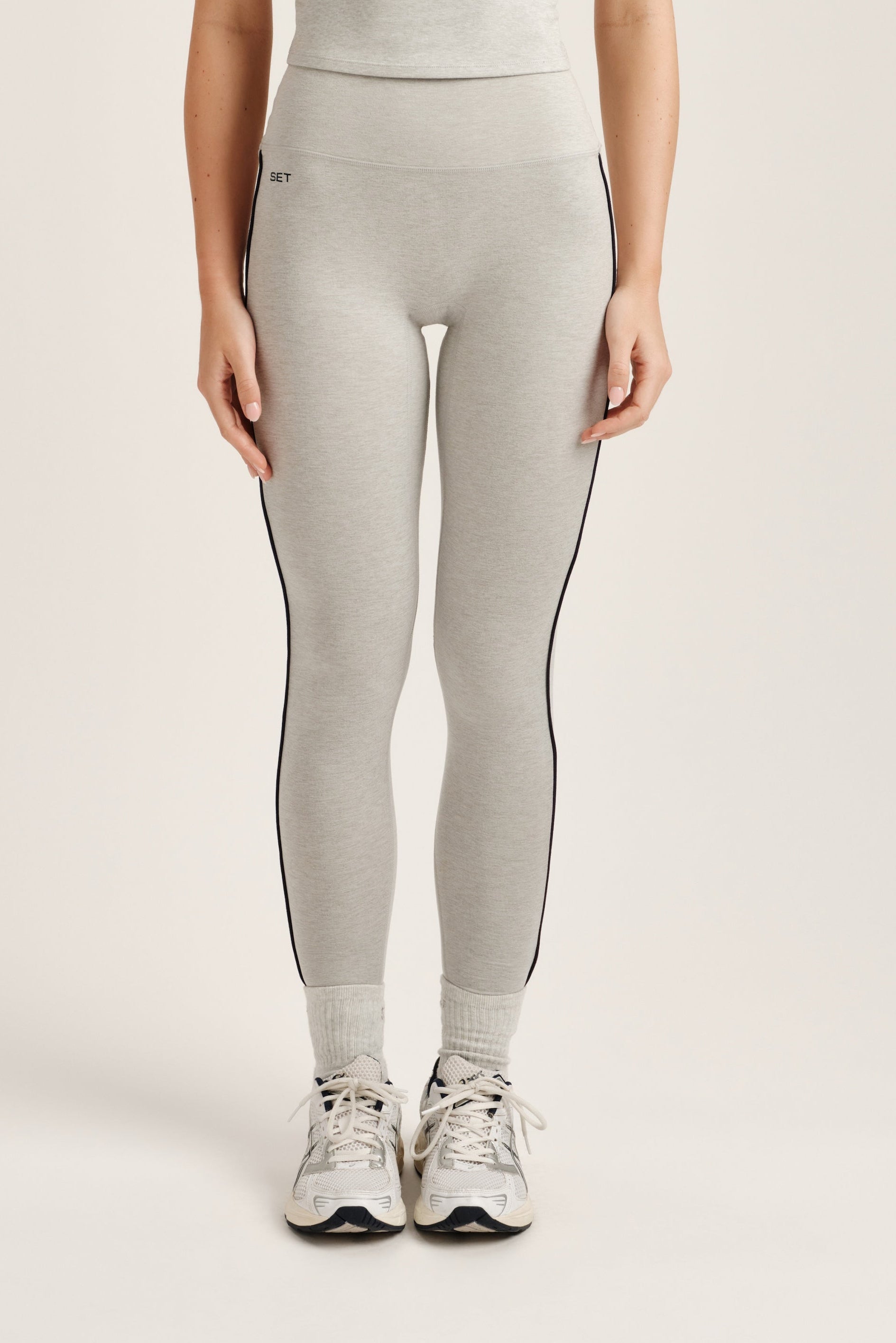 Person wearing gray leggings with a subtle pattern on a light background <model-info>Bella wears a size XS and is 5’7, 23” waist, 32AB bust.</model-info>