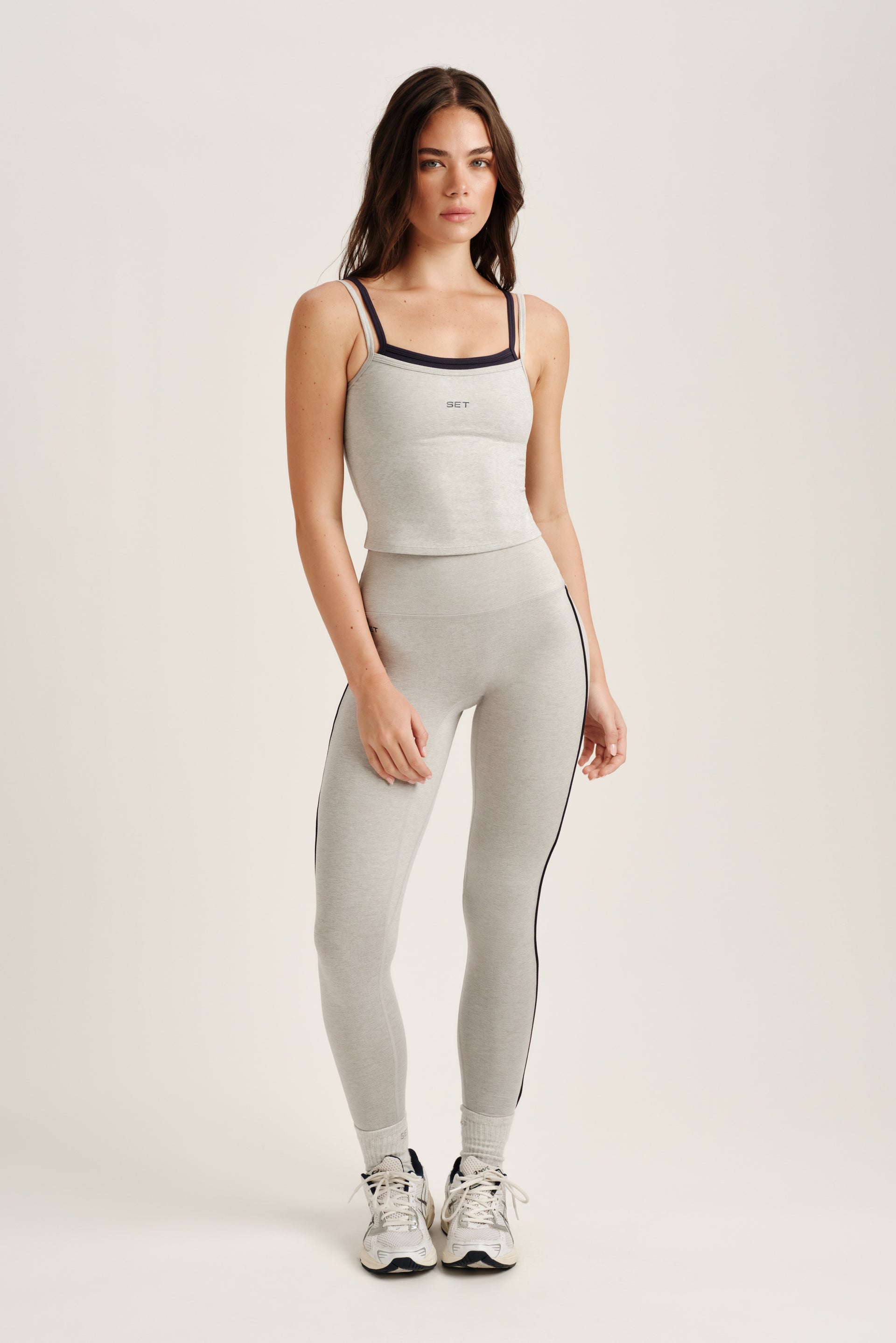 Woman wearing a gray athletic outfit with a white background