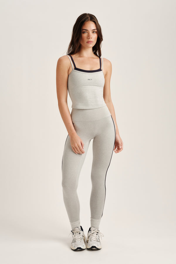 Woman wearing a gray athletic outfit with a white background