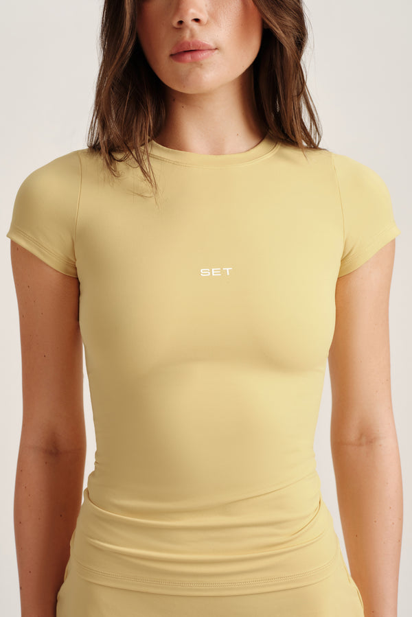 Woman wearing a yellow t-shirt with 'SET' logo on a white background