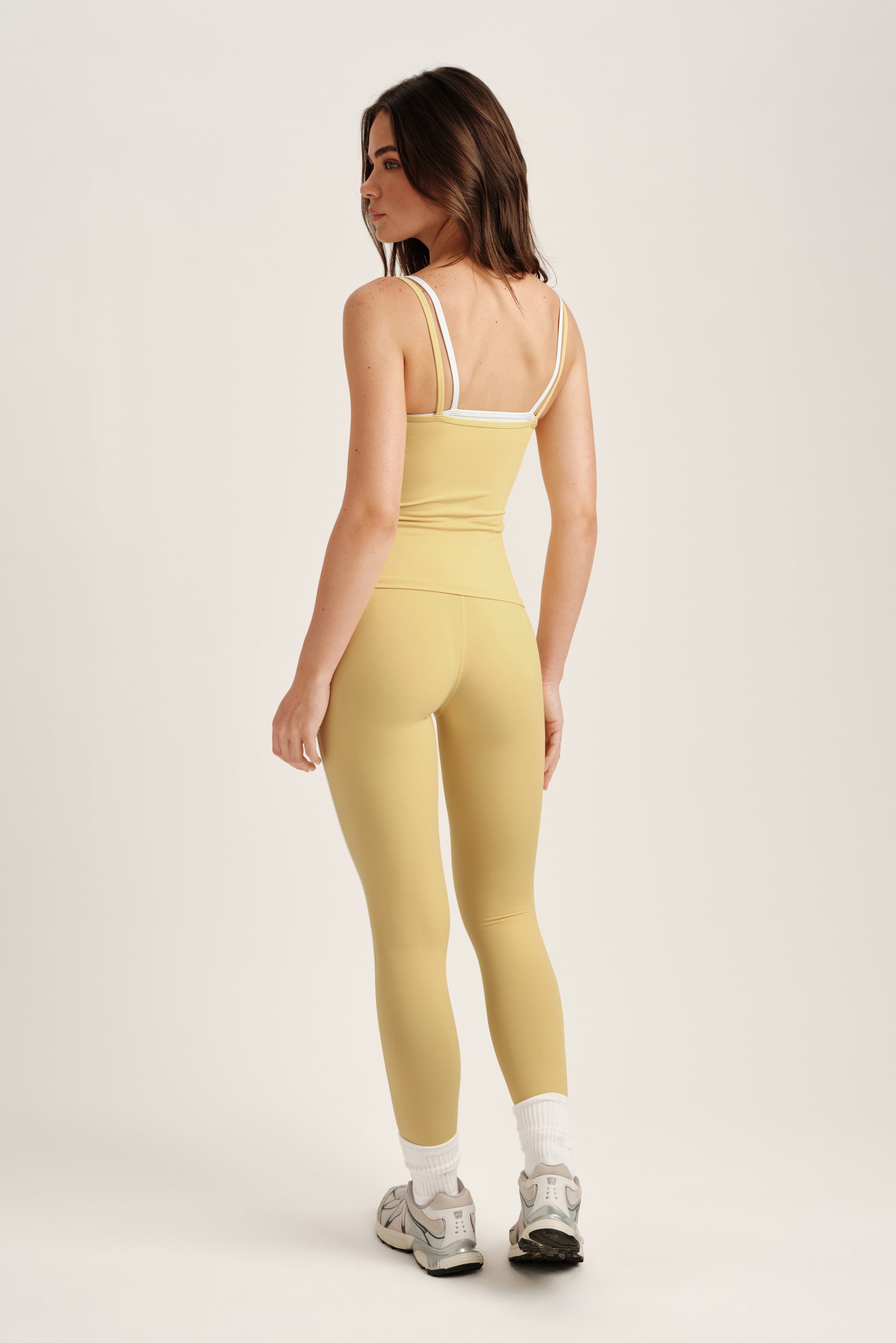 Woman wearing a yellow jumpsuit on a white background