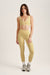 Woman wearing a yellow sports bra and leggings set on a white background