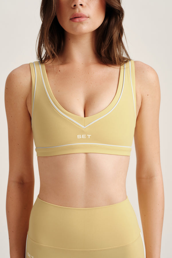 Woman wearing a yellow sports bra and leggings with 'SET' branding on a light background