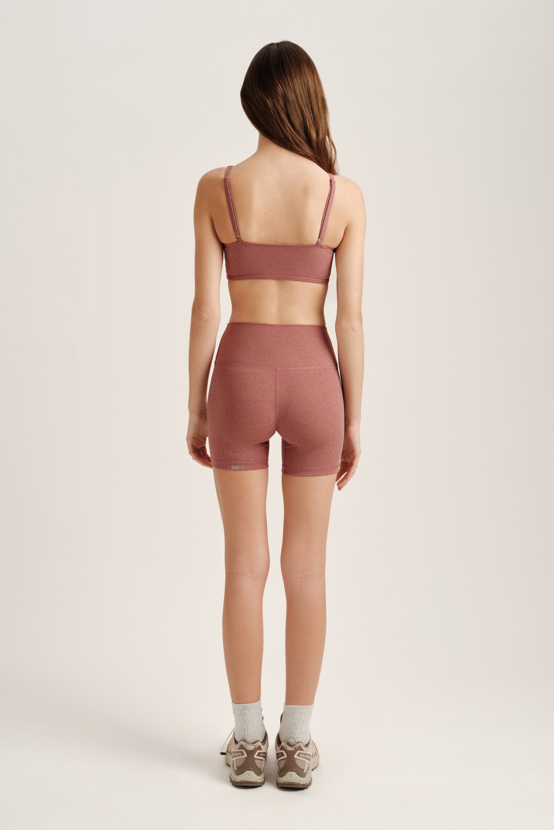 Person wearing a pink sports bra and shorts set on a white background