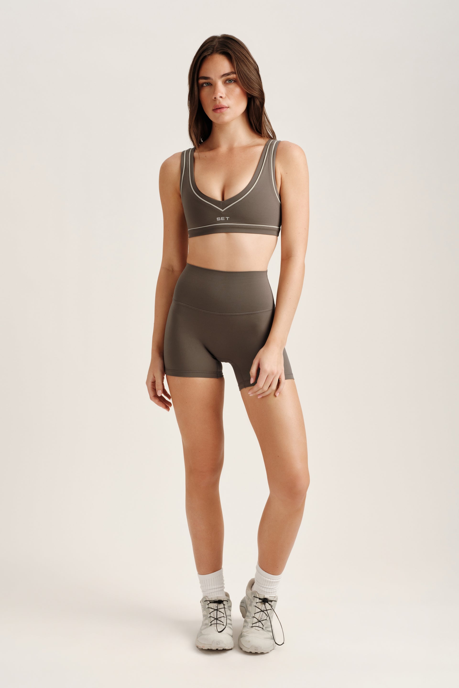 Woman wearing a green sports bra and shorts set on a white background