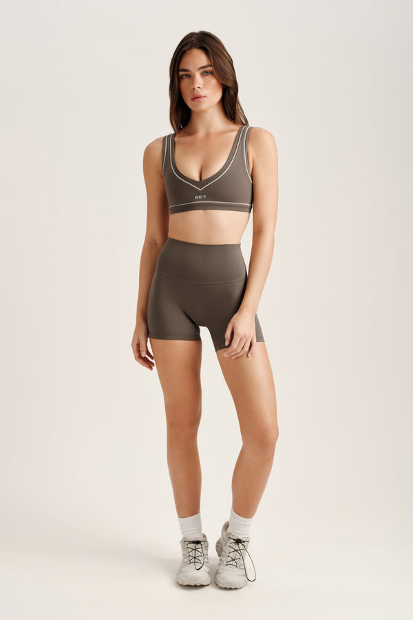 Woman wearing a green sports bra and shorts set on a white background