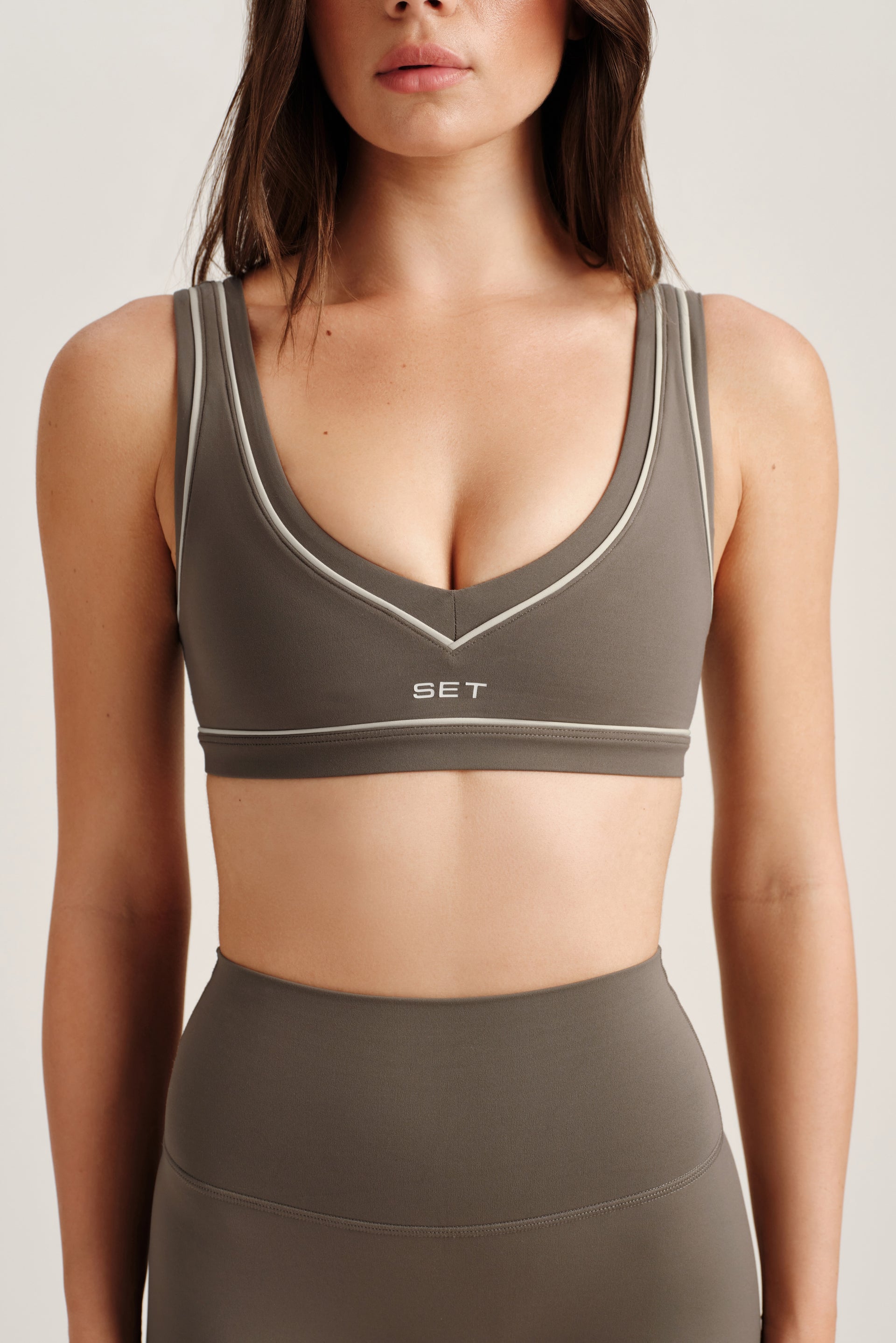 Woman wearing a gray sports bra and leggings with 'SET' branding on a light background
