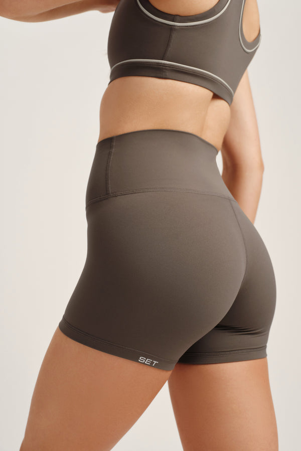 Person wearing a green sports bra and shorts set on a plain background