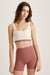 Woman wearing a beige sports bra and maroon shorts on a light background <model-info>Kalia wears a size XS and is 5’9 , 23” waist, 32B bust.</model-info>