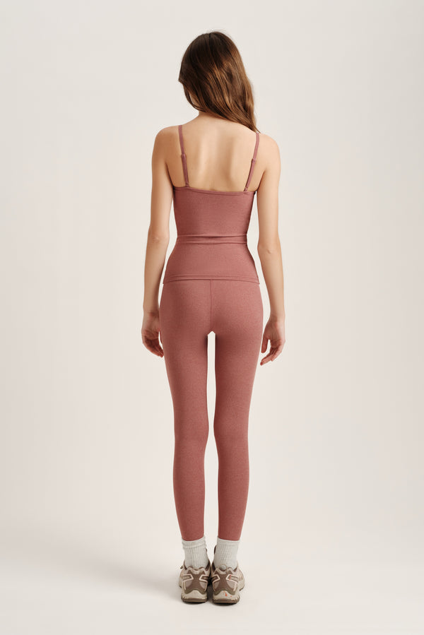 Person wearing a pink tank top and leggings on a white background