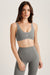 Woman wearing a gray sports bra and leggings on a light background <model-info>Bella wears a size XS and is 5’7, 23” waist, 32AB bust.</model-info>