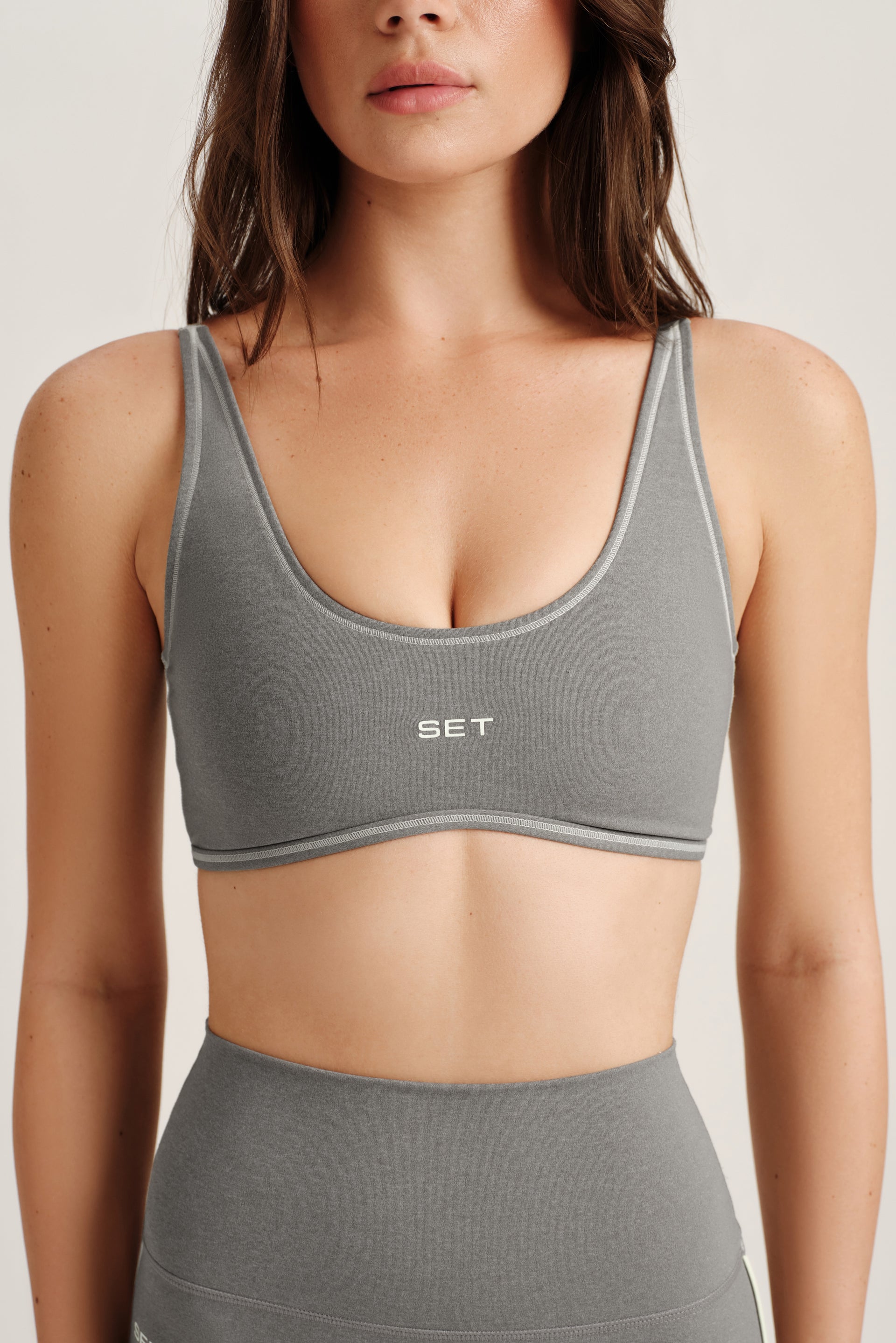 Woman wearing a gray sports bra and leggings with 'SET' branding.
