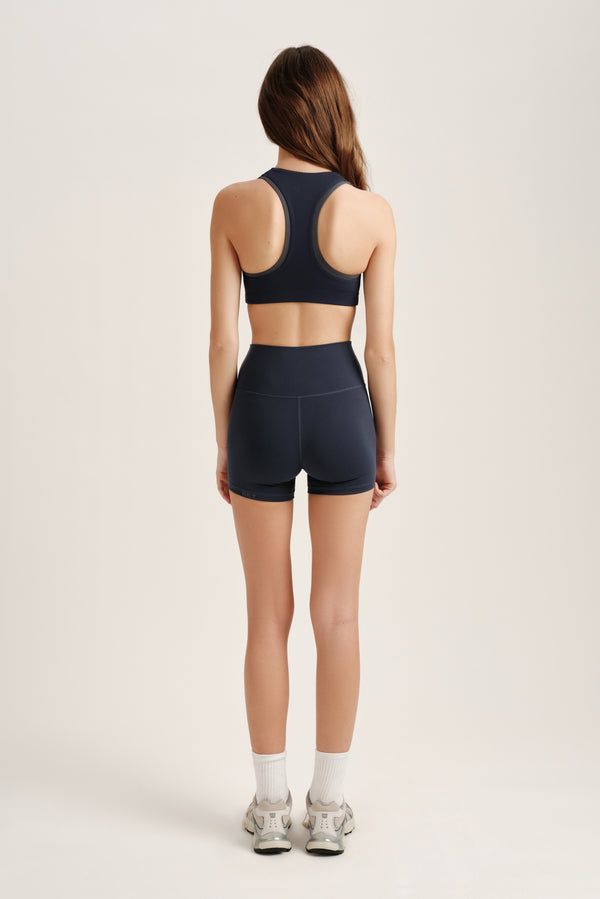 Person wearing a navy sports bra and shorts set on a light background