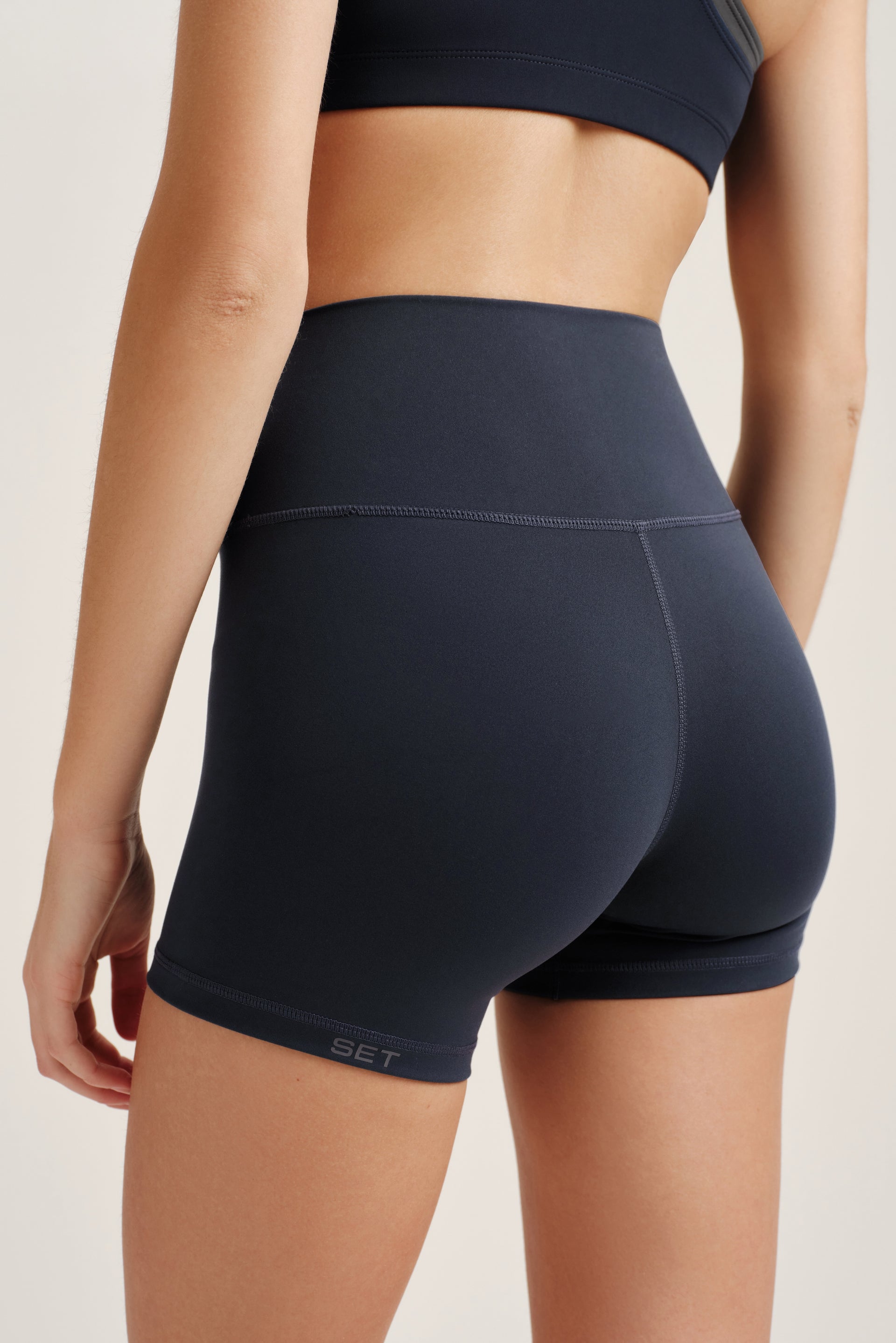 Person wearing black athletic shorts and top on a light background