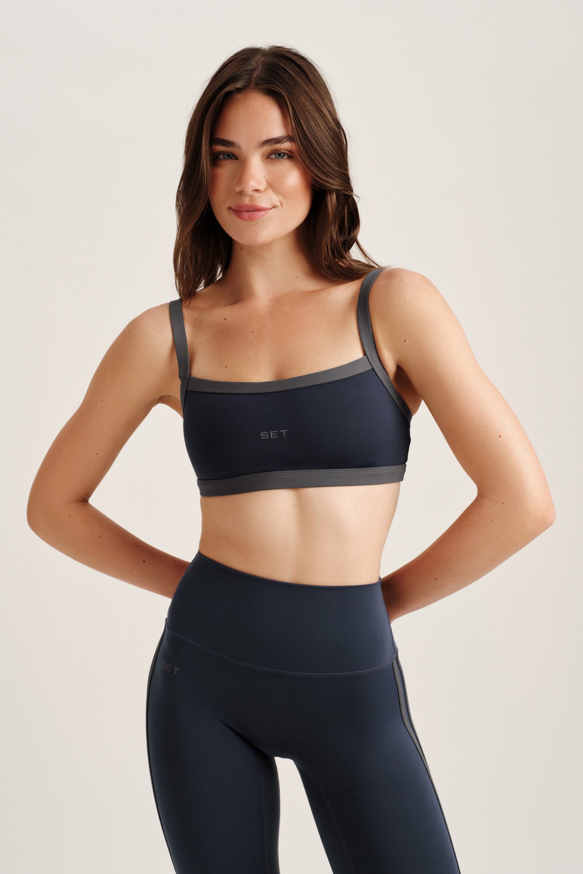 Woman wearing a black sports bra and leggings on a light background 
