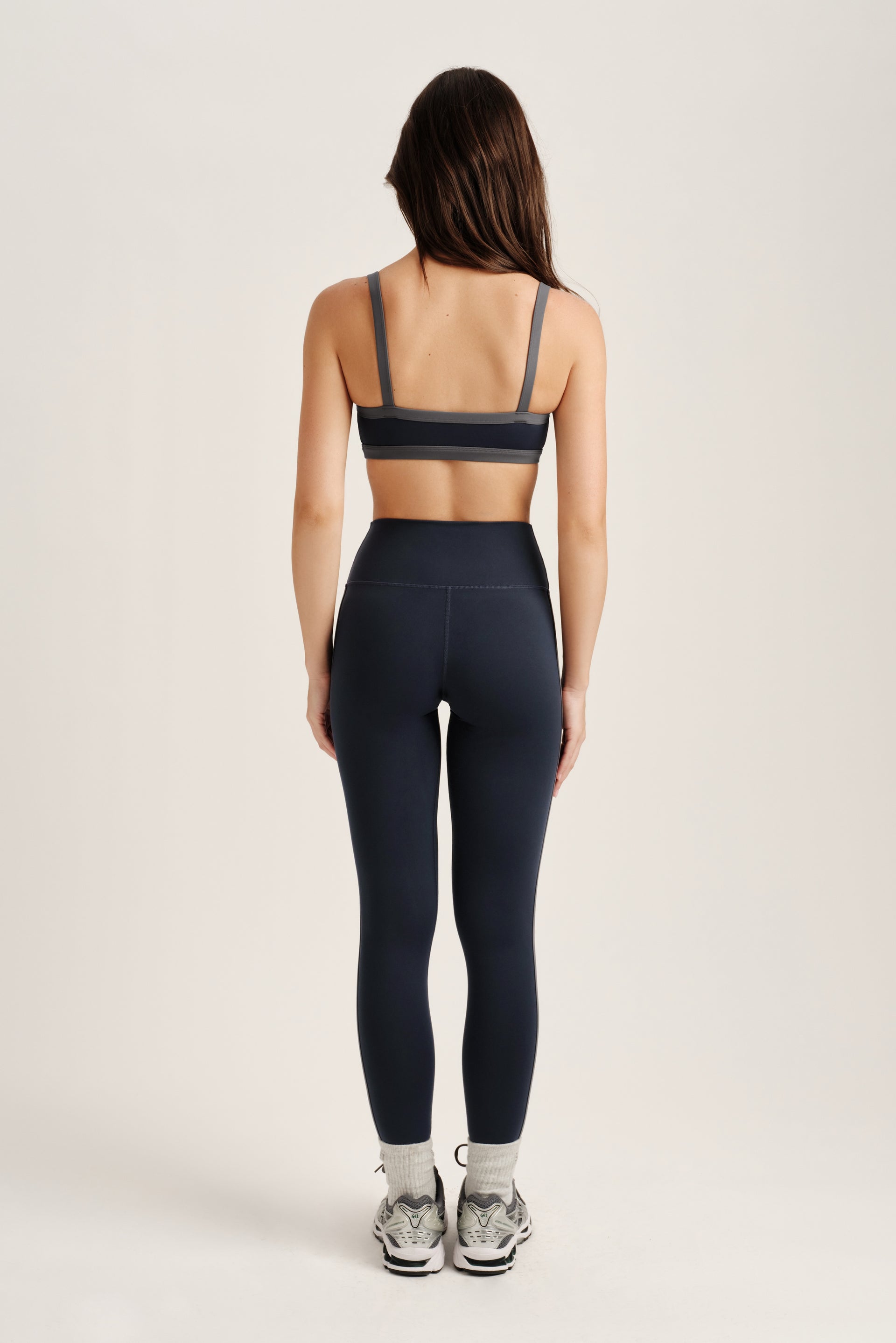 Person wearing a navy sports bra and leggings set on a light gray background