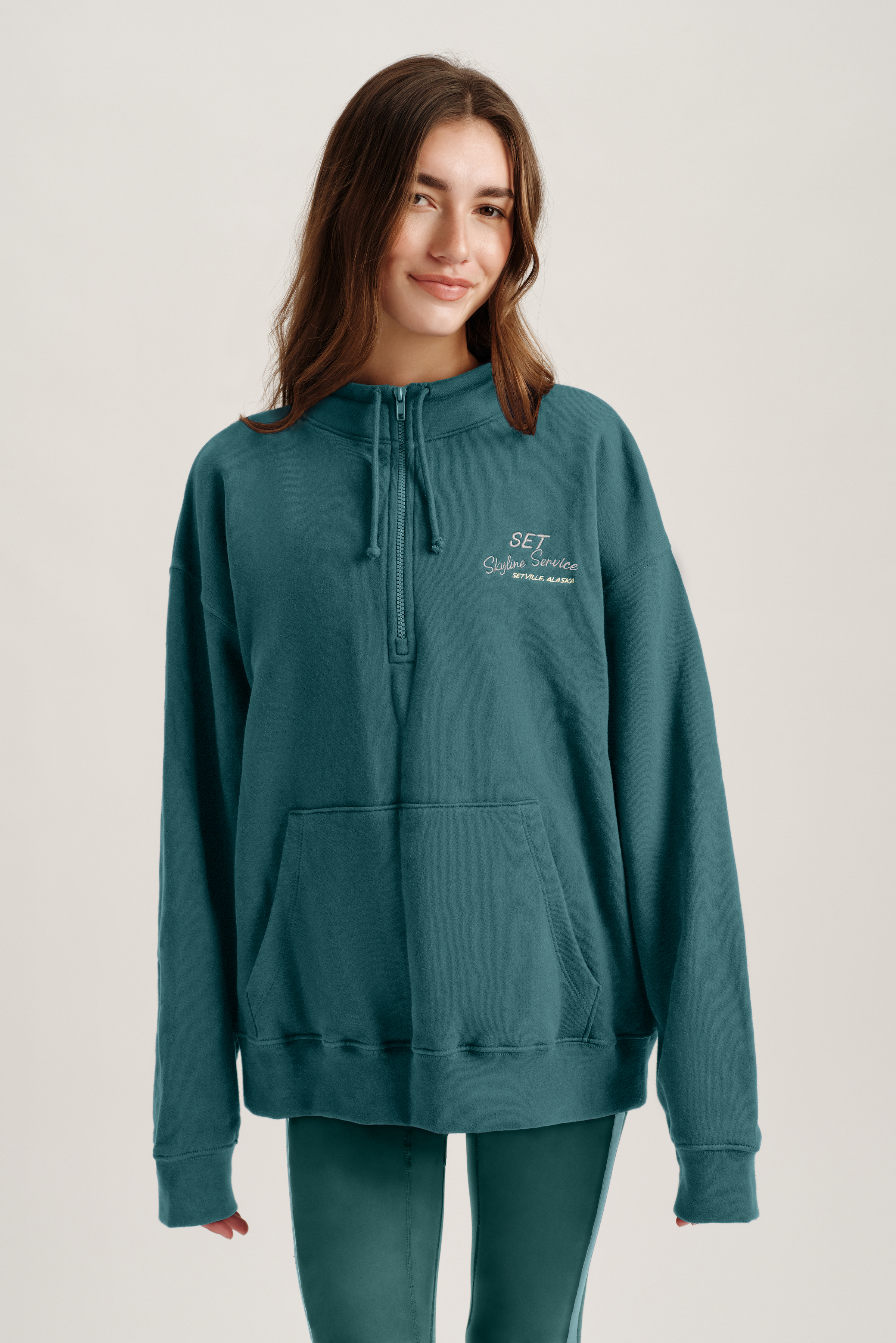 Person wearing a teal hoodie with text on a plain background 