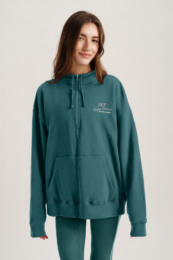 Person wearing a teal hoodie with text on a plain background 