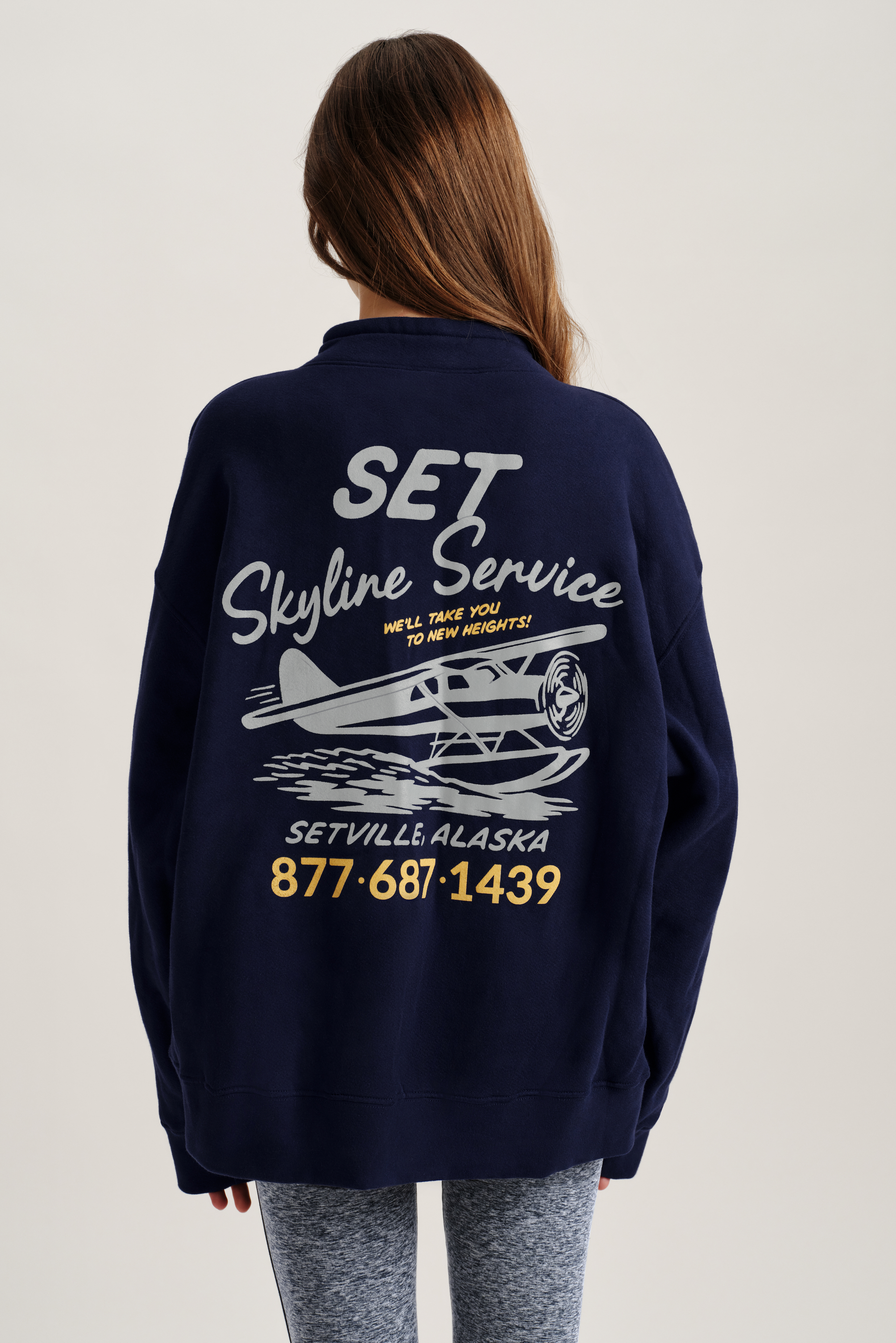 Person wearing a navy blue sweatshirt with 'Set Skyline Service' text and airplane graphic on the back.