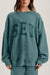 Person wearing a teal sweatshirt with 'SET' printed on it against a neutral background