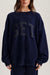 Person wearing a navy blue sweatshirt with 'SET' printed on it against a neutral background