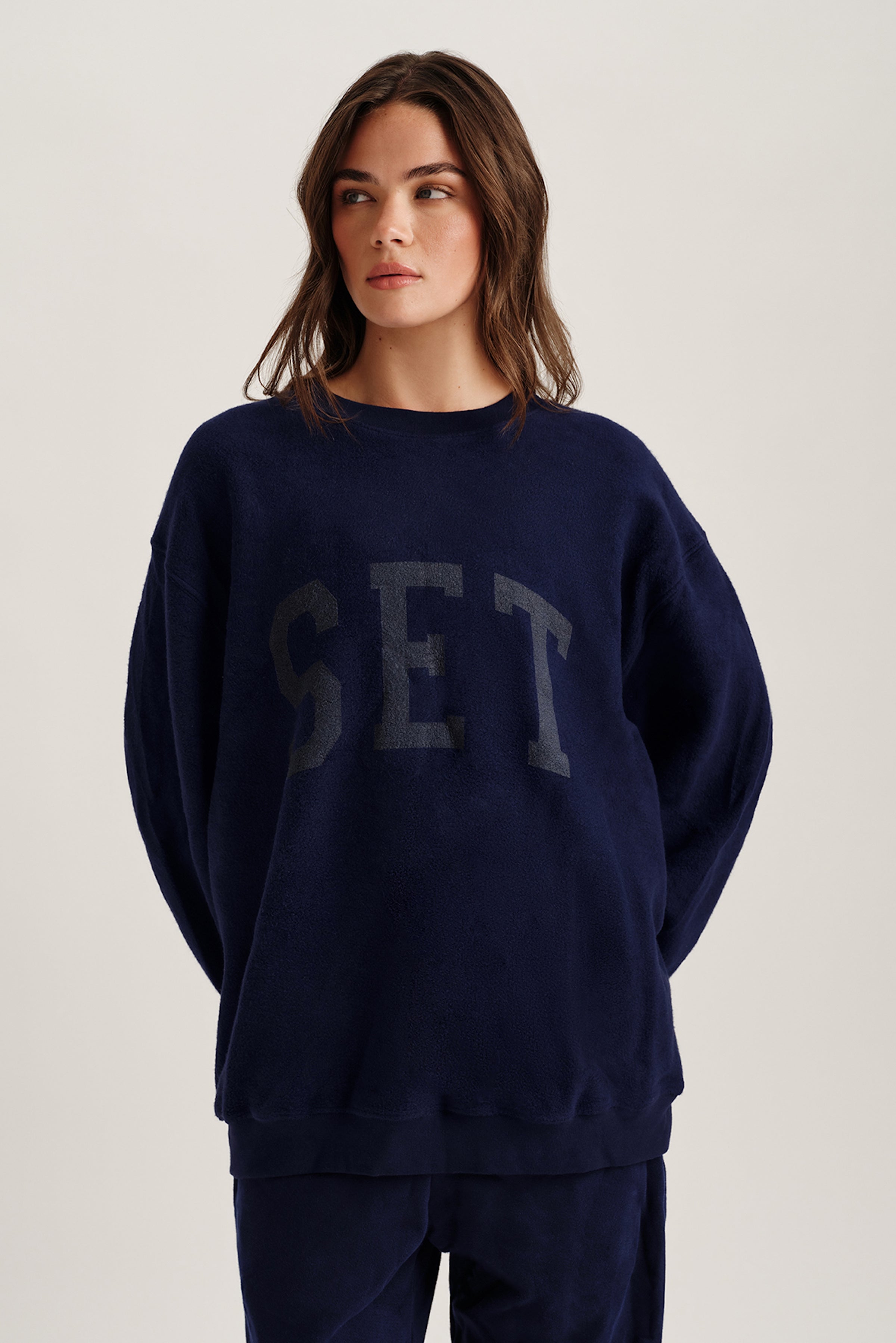 Person wearing a navy blue sweatshirt with 'SET' text on a light background 
