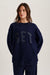 Person wearing a navy blue sweatshirt with 'SET' text on a light background <model-info>Bella wears a size XS/S and is 5’7, 23” waist, 32AB bust.</model-info> 