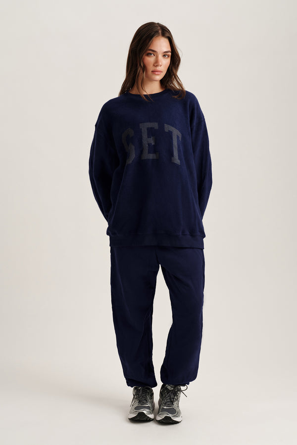 Person wearing a navy blue sweatshirt and pants with 'SET' text on a white background
