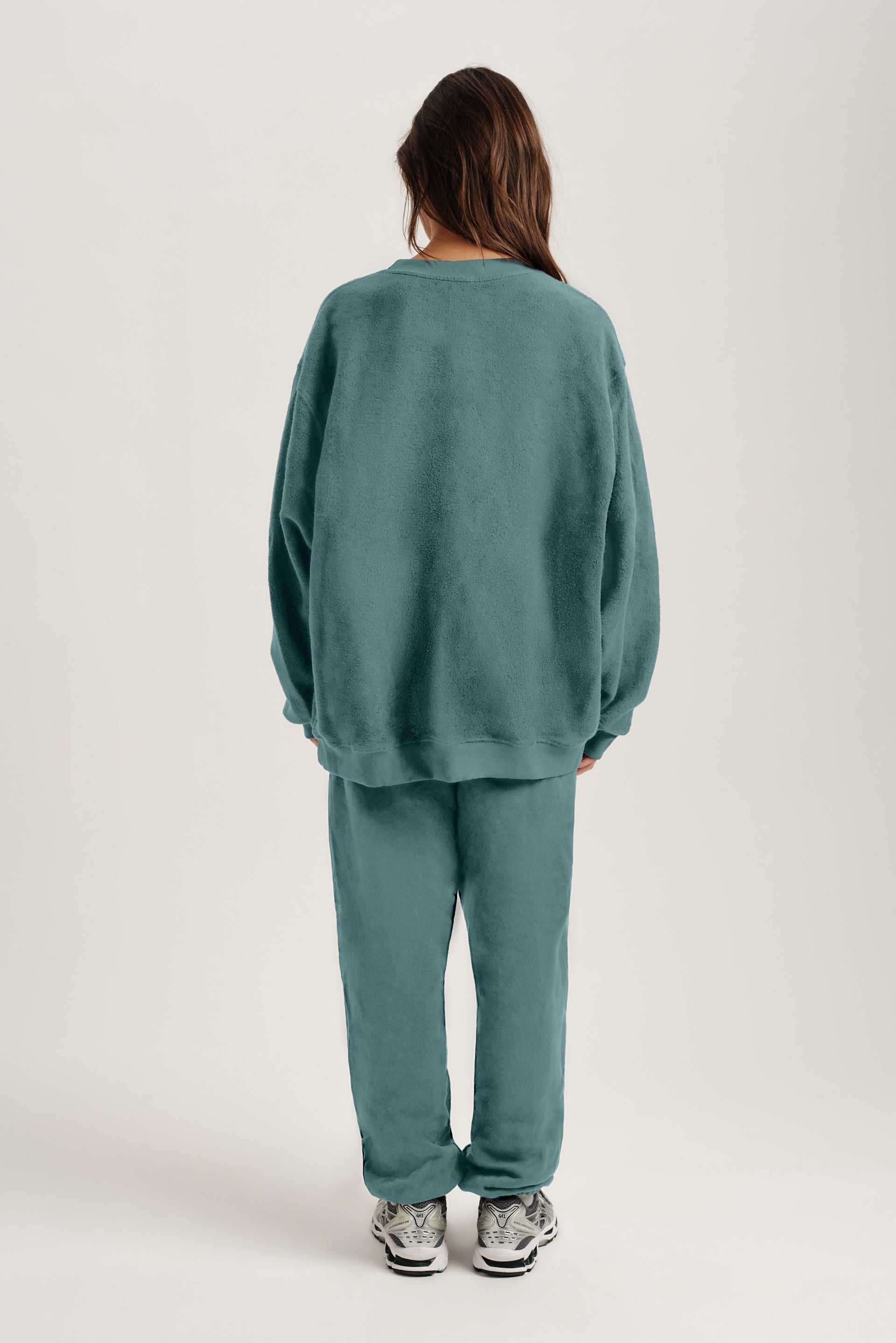 Person wearing a teal sweat set on a white background