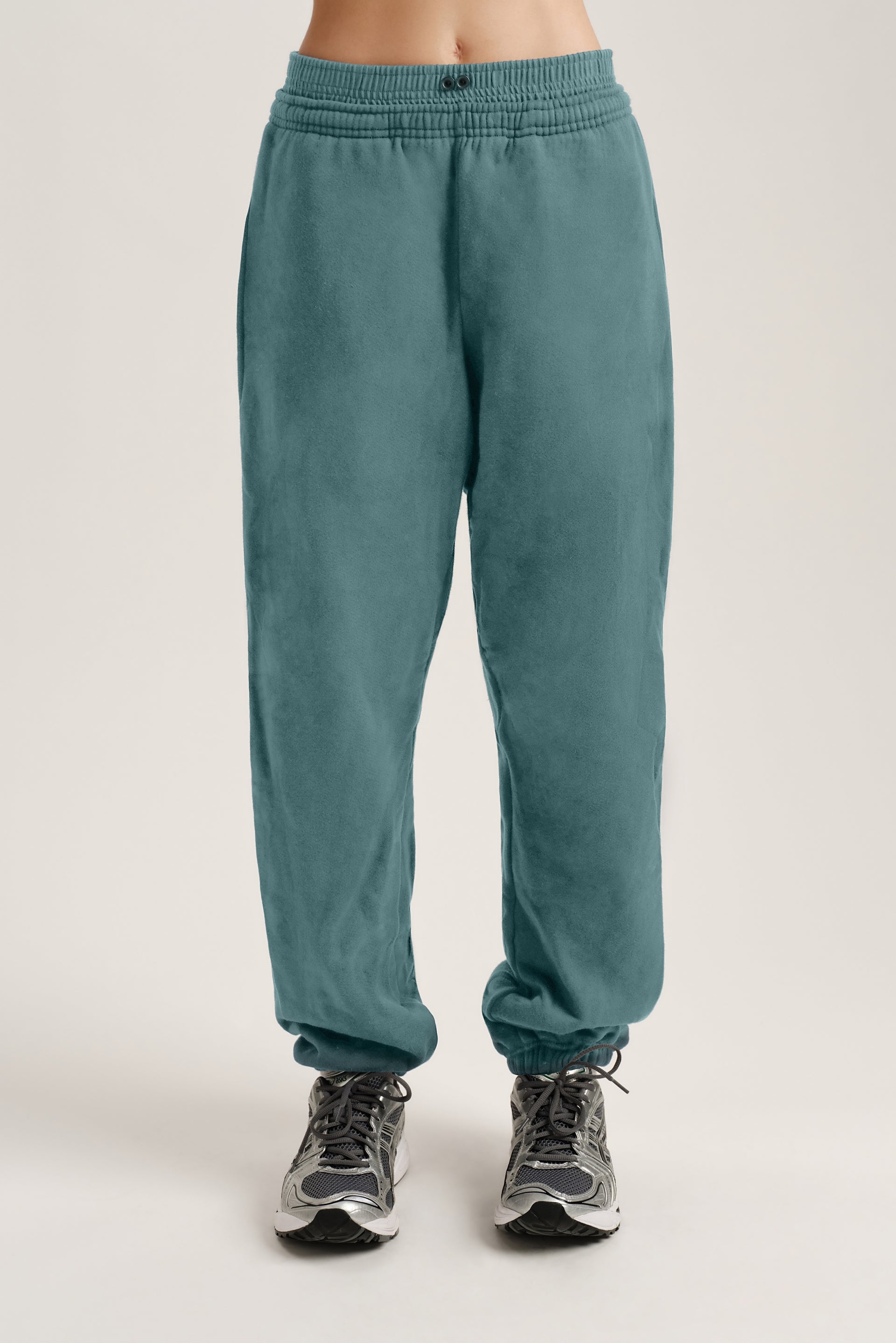 Teal sweatpants worn by a person on a plain background <model-info>Bella wears a size S and is 5’7, 23” waist, 32AB bust.</model-info> 